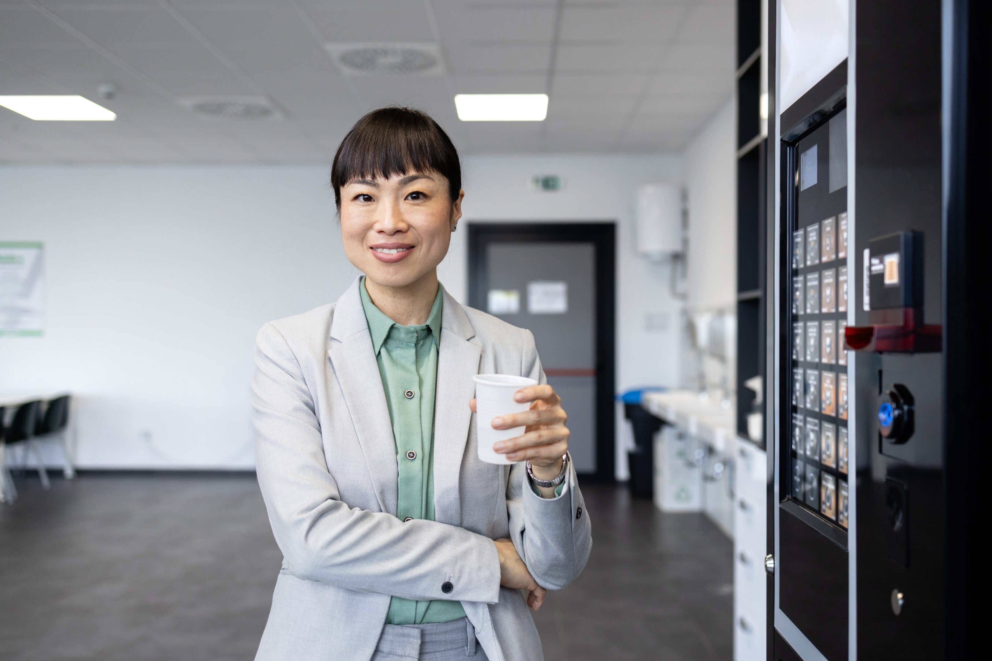 Businesswoman holding coffee in office break room.