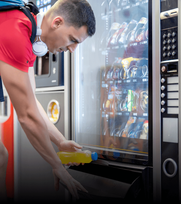 Man retrieving drink from vending machine.